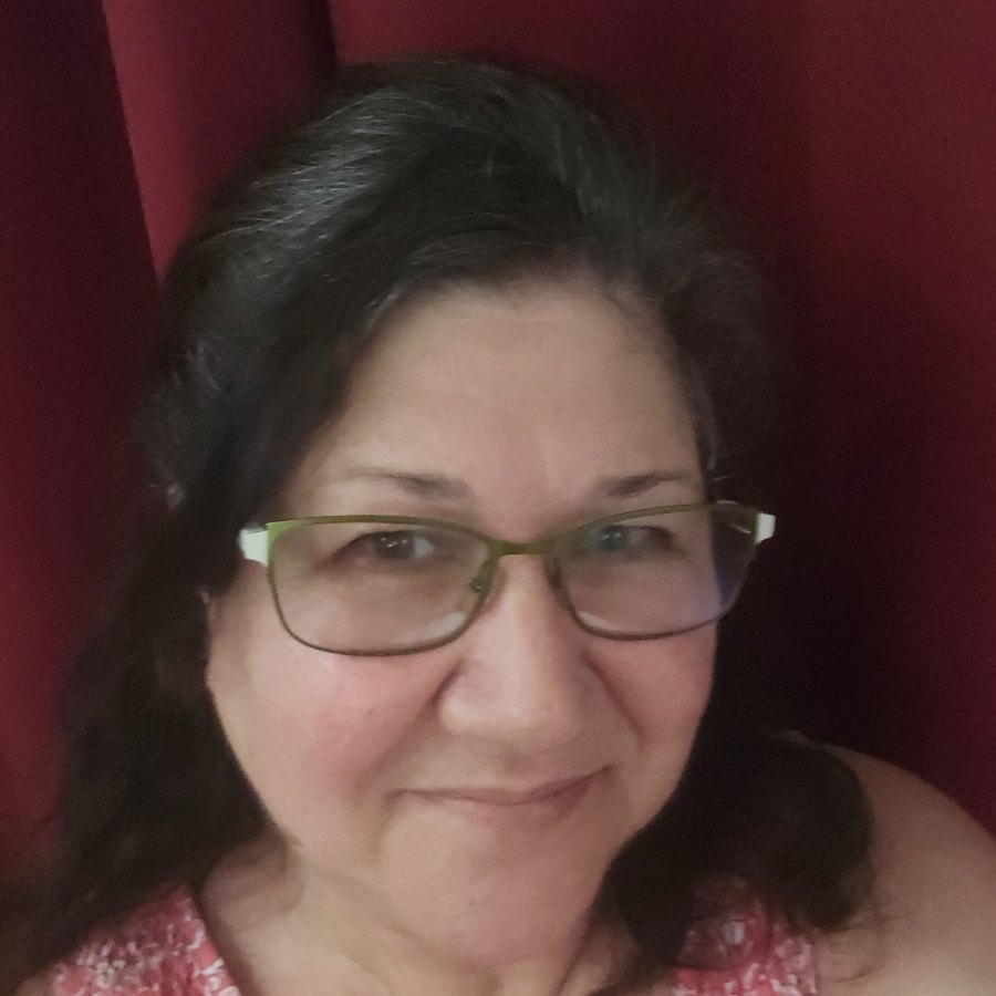 Gina Saporito, founder of Little Saporito Press, smiling and wearing green-rimmed glasses.